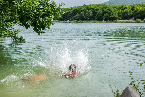 Young man jumping into the water from the cliff.