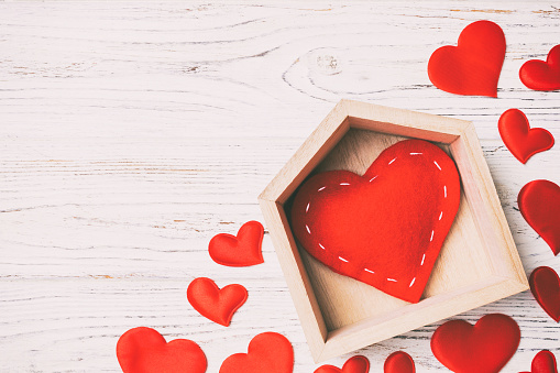 Top view of red heart in a house decorated with small hearts on wooden background. Valentine's day. Home sweet home concept.