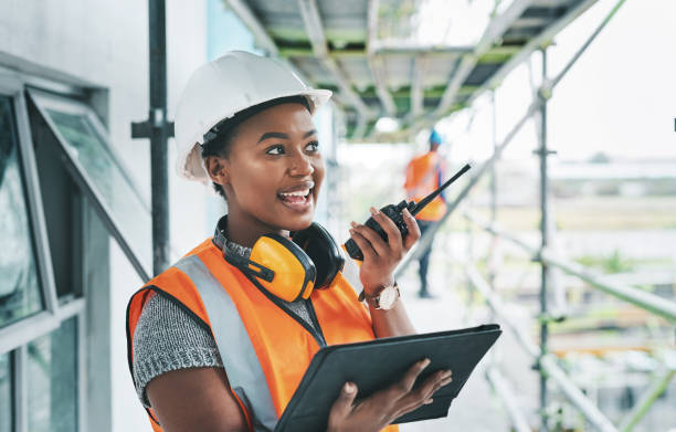 Facilitating better communication and collaboration through management tools Shot of a young woman using a digital tablet and walkie talkie while working at a construction site walkie talkie photos stock pictures, royalty-free photos & images