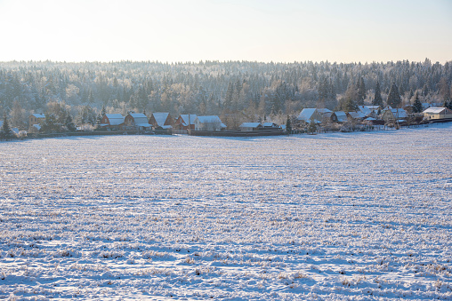 Winter frosty landscape. A snow-covered village on the edge of a wide field.