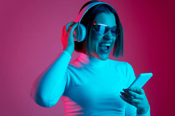 istock Caucasian woman's portrait isolated on pink studio background in multicolored neon light 1298572419