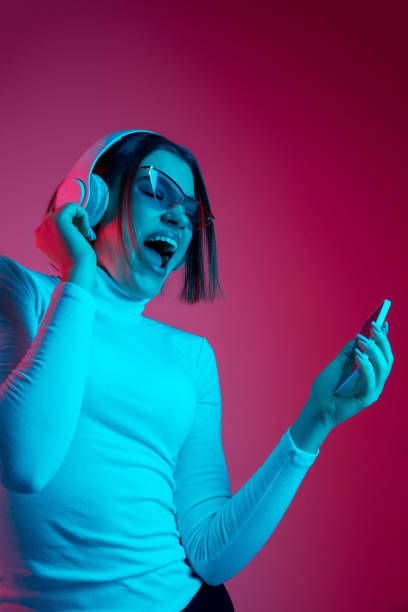 istock Caucasian woman's portrait isolated on pink studio background in multicolored neon light 1298572426