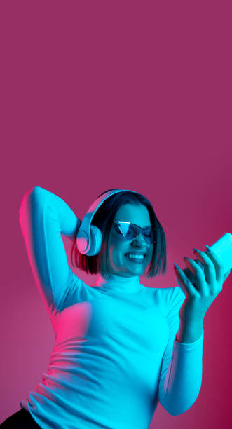 istock Caucasian woman's portrait isolated on pink studio background in multicolored neon light 1298572432