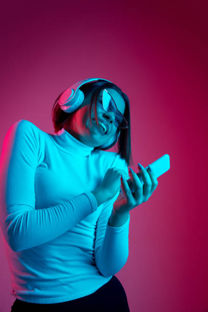 istock Caucasian woman's portrait isolated on pink studio background in multicolored neon light 1298572435
