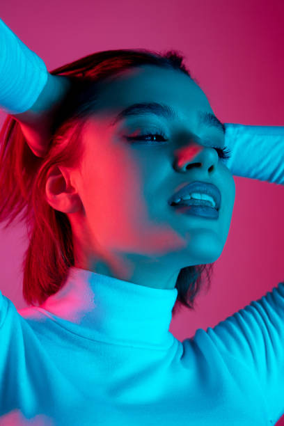 istock Caucasian woman's portrait isolated on pink studio background in multicolored neon light 1298572455