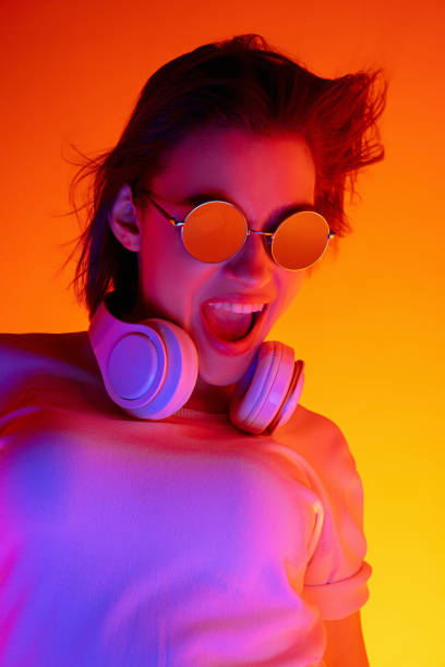 istock Caucasian woman's portrait isolated on orange studio background in multicolored neon light 1298572488