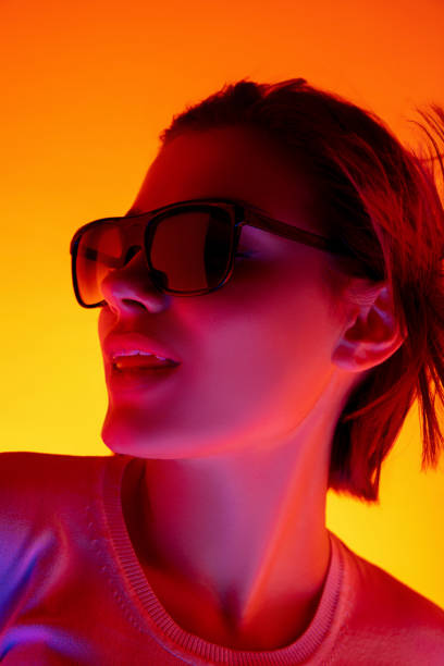 istock Caucasian woman's portrait isolated on orange studio background in multicolored neon light 1298572495