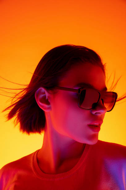 istock Caucasian woman's portrait isolated on orange studio background in multicolored neon light 1298572500