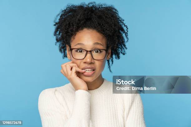 Shy Awkward Afro Woman Wear Glasses Biting Finger Feeling Embarrassed Confused And Nervous Studio Stock Photo - Download Image Now