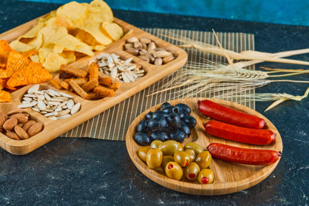 istock Assorted snacks, a plate of sausages and olives on dark table 1298573059