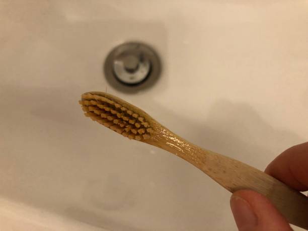 istock Hand holds bamboo toothbrush over sink 1298574246