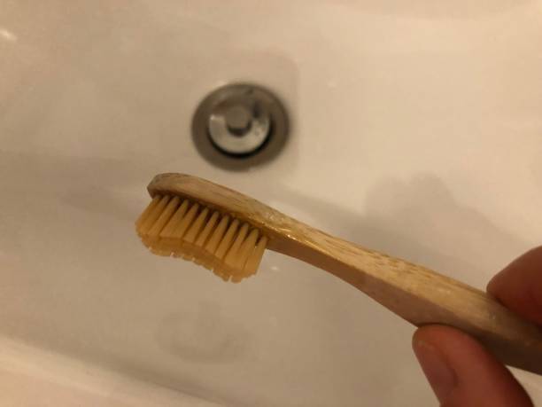 istock Hand holds bamboo toothbrush over sink 1298574260