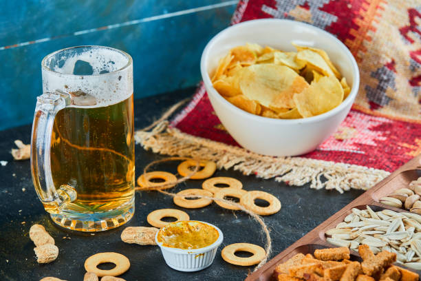 istock Assorted snacks, chips and a glass of beer on dark table 1298574284