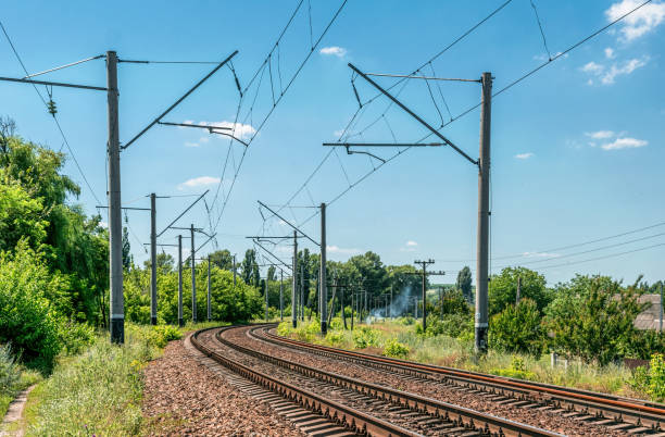 Summer Seasonal Rural Landscape and Suburban Railway Old rusty suburban railroad track in the countryside. Sunny summer industrial landscape in Eastern Europe electric train photos stock pictures, royalty-free photos & images