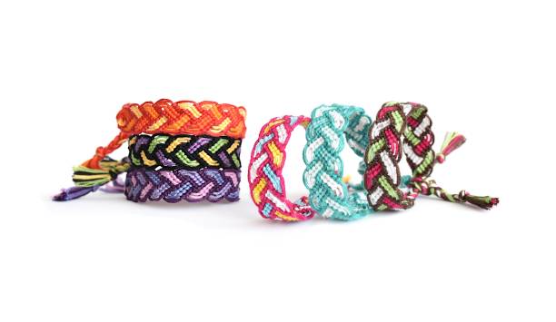 istock Selective focus of multi-colored woven DIY friendship bracelets Pigtail handmade of embroidery bright thread with knots isolated on white background 1298582033