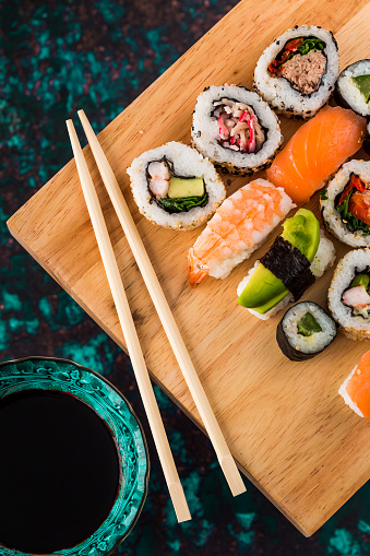 Japanese food restaurant delivery - sushi maki, unagi and roll platter set isolated on blue wood background, above view