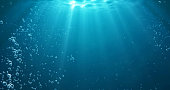 istock Underwater background with water bubbles and undersea light rays shine 1298585936