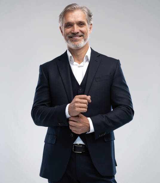 istock Handsome smiling middle-aged man in suit posing against grey background 1298586650