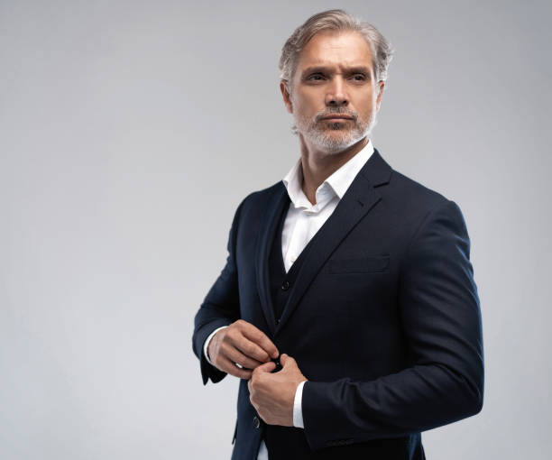 istock Handsome middle-aged man in suit posing against grey background 1298586662