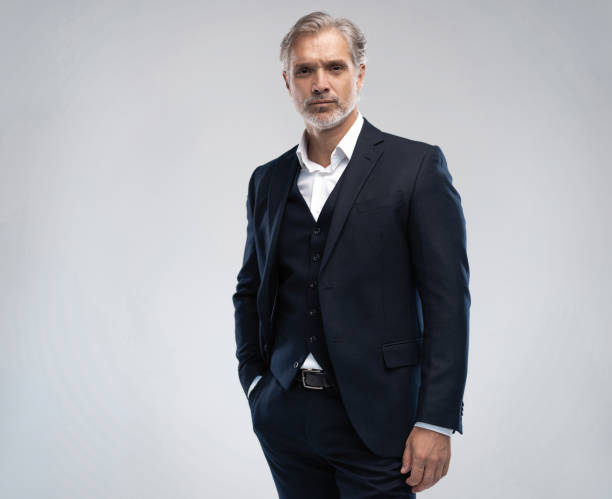 istock Handsome middle-aged man in suit posing against grey background 1298586668