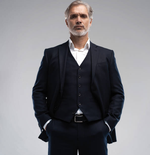 istock Handsome middle-aged man in suit posing against grey background 1298586671