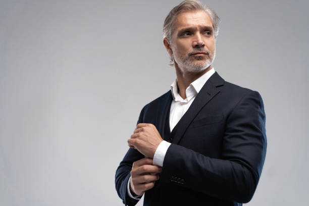 istock Handsome middle-aged man in suit posing against grey background 1298586674