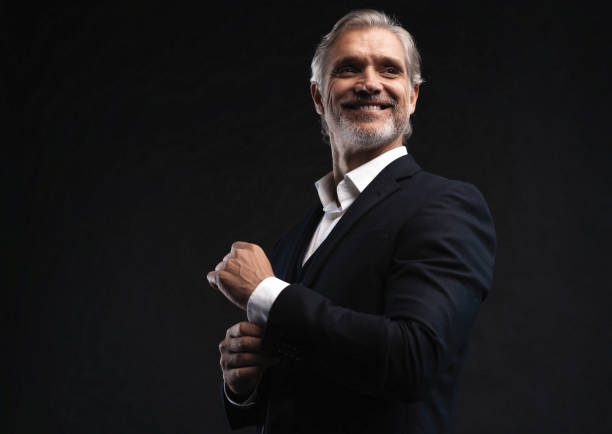 istock Handsome middle-aged man in suit posing against black background 1298586754