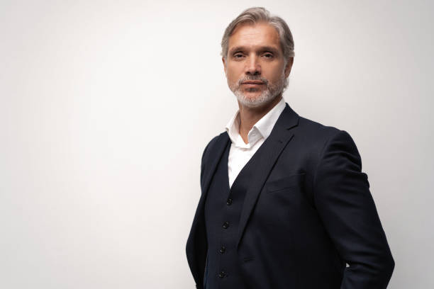 istock Handsome middle-aged man in suit posing against grey background 1298587963