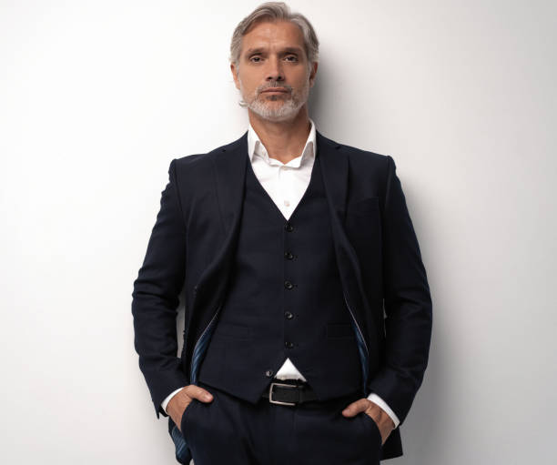 istock Handsome middle-aged man in suit posing against grey background 1298587968