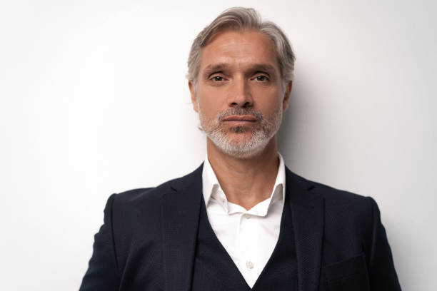 istock Handsome middle-aged man in suit posing against grey background 1298587974
