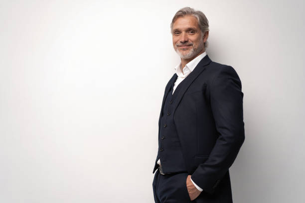 istock Handsome middle-aged man in suit posing against grey background 1298587987