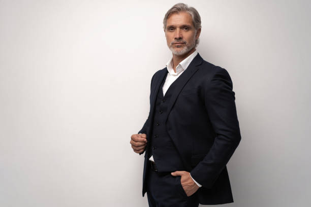 istock Handsome middle-aged man in suit posing against grey background 1298587992
