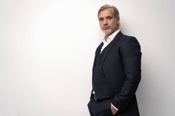 istock Handsome middle-aged man in suit posing against grey background 1298588003