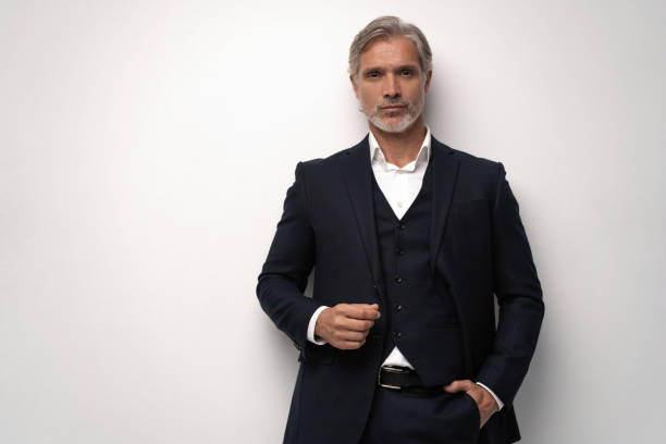istock Handsome middle-aged man in suit posing against grey background 1298588013