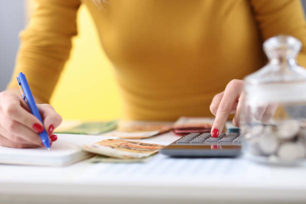 as mãos das mulheres estão segurando caneta e estão contando notas na calculadora - currency pen wealth paper currency - fotografias e filmes do acervo