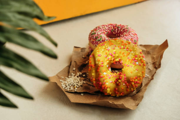 round glazed sweet doughnuts with sprinkles in shade under palm tree in bright sun fade and melt. Tropical concept, food blog, selective Focus round glazed sweet doughnuts with sprinkles in shade under palm tree in bright sun fade and melt. Tropical concept, food blog, selective Focus fade in stock pictures, royalty-free photos & images