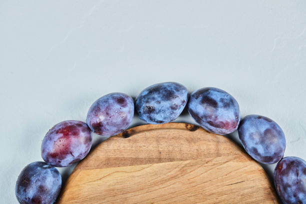 Group of fresh plums around the wooden plate