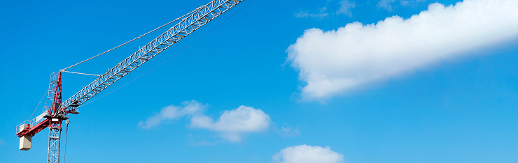 A construction crane on a blue sky background. The concept of construction and repair.