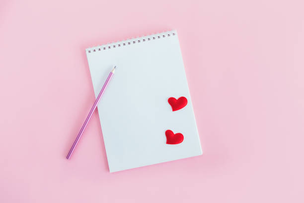 istock Notebook with blank page, pencil and red hearts on a pink background. 1298593209