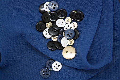 Blue, white and black buttons on blue fabric. Space for text.