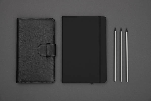 istock Black leather cover notebook flat lay over grey 1298598137
