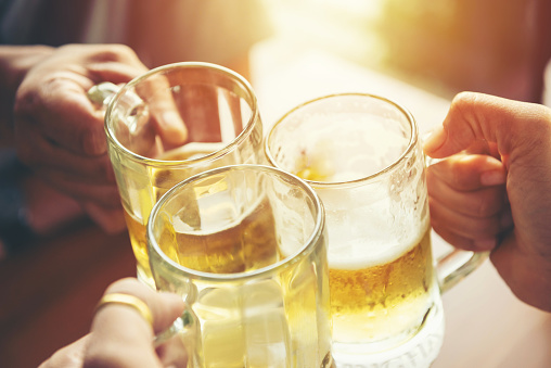 Close up of hands clinking beer mugs at party. people, leisure and drinks relax concept