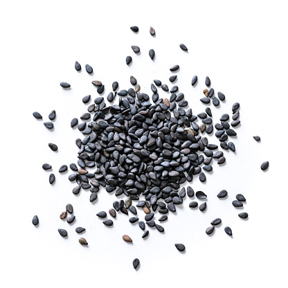 Overhead view of black sesame seeds heap spilled on white background. High resolution 28Mp studio digital capture taken with Sony A7rII and Sony FE 90mm f2.8 macro G OSS lens