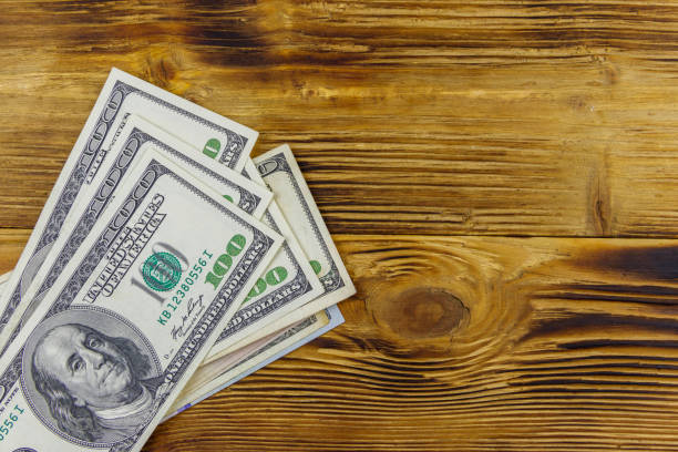 istock Stack of one hundred dollars bills on wooden desk 1298605126