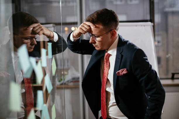istock Exhausted businessman in conference room use sticky notes on glass wall. 1298606739