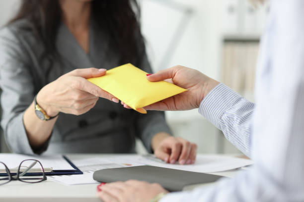 Woman hands over full envelope to her interlocutor Woman hands over full envelope to her interlocutor. Salary in an envelope concept bribing stock pictures, royalty-free photos & images