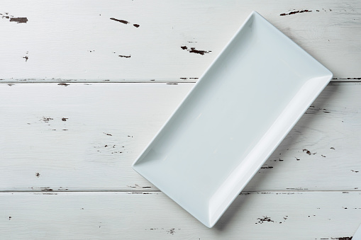 Vista superior de una placa rectangular blanca sobre un fondo de madera blanca. photo