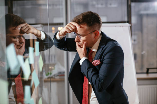 istock Exhausted businessman in conference room use sticky notes on glass wall. 1298610046