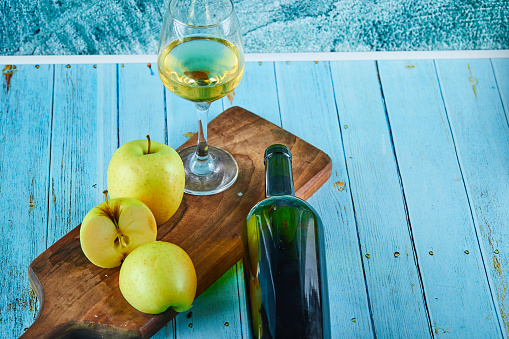 Apple slices on wooden cutting board with a glass of wine and bottle. High quality photo