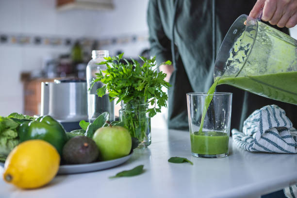 Woman preparing green smoothie in the kitchen stock photo